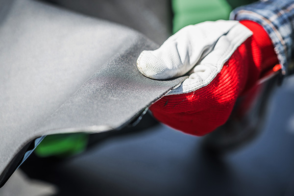 Un techador sostiene una lámina de EPDM en una mano con guante.