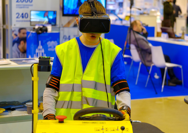 Niño usando un casco de realidad virtual y un simulador de construcción en una convención.