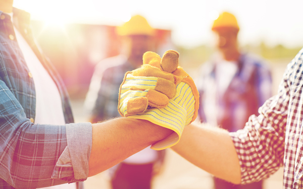 Dos trabajadores de la construcción inclinándose para estrecharse las manos