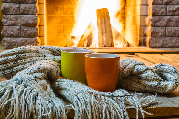 Dos tazas y una manta frente a una chimenea crepitante