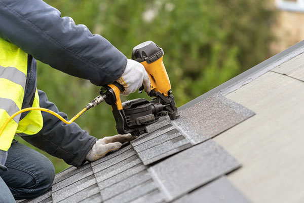 Un propietario de vivienda instalando tejas.