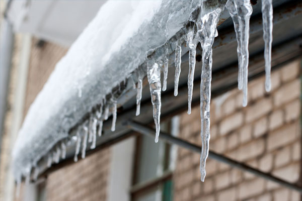 Un techo cubierto de hielo con carámbanos que cuelgan del borde