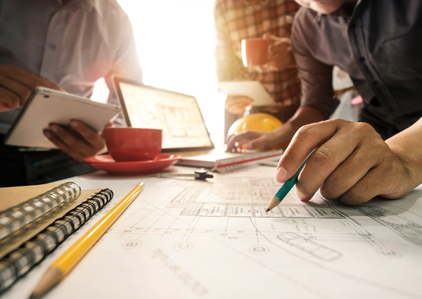 Tres contratistas esbozan ideas de marketing en un escritorio con café y computadoras portátiles