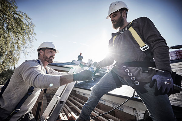 A roofing crew member works on a roof.