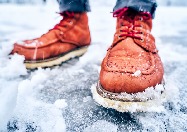 Imagen en primer plano de las botas de una persona en condiciones de nieve y hielo