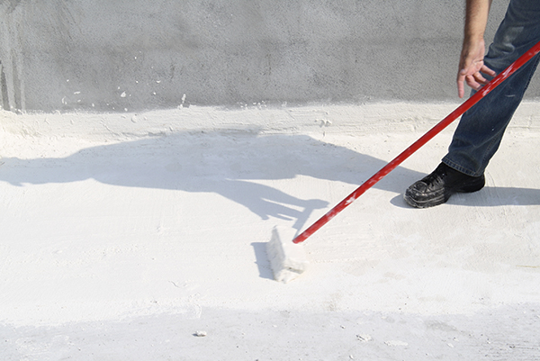 Un techador aplicando un recubrimiento para techo blanco.